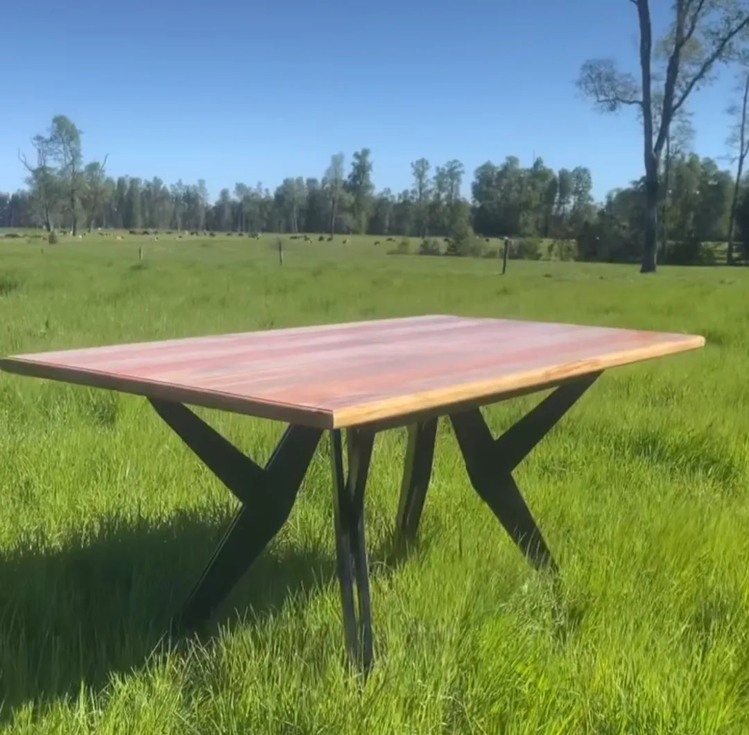 Mesa de madera con patas de fierro negro sobre el pasto